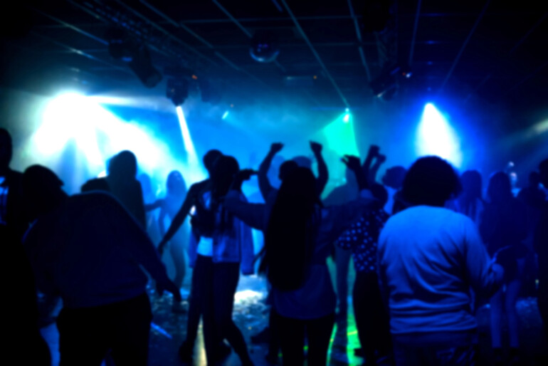 People dancing under colorful lights in a Barcelona nightclub
