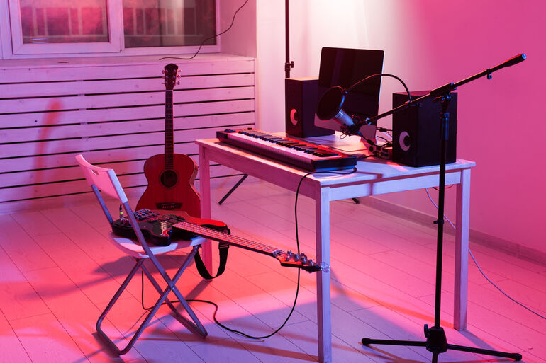 A customized music space with a synthesizer keyboard, a digital recording, and guitars