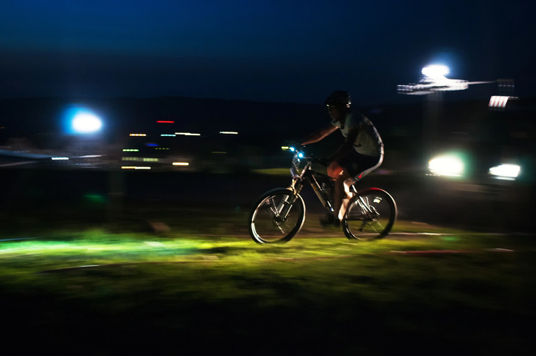 A person riding a bike at night with lights illuminating the path