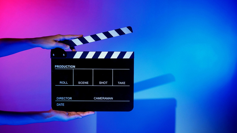Film clapperboard held in vibrant studio lighting, representing the creative process of crafting compelling music videos