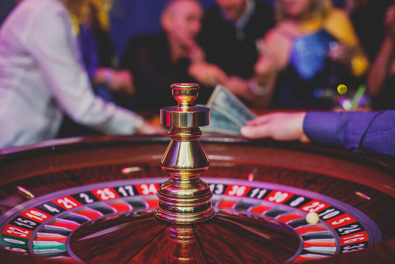 Roulette wheel in a casino, with people in the background listening music and gossiping