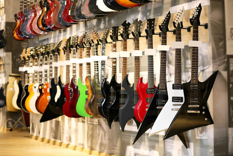 Guitars hanging in a guitar shop, reflecting how the business side of music shapes what we hear.