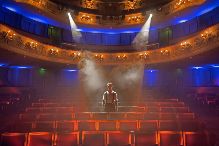 Stage actor under spotlight in an empty theater