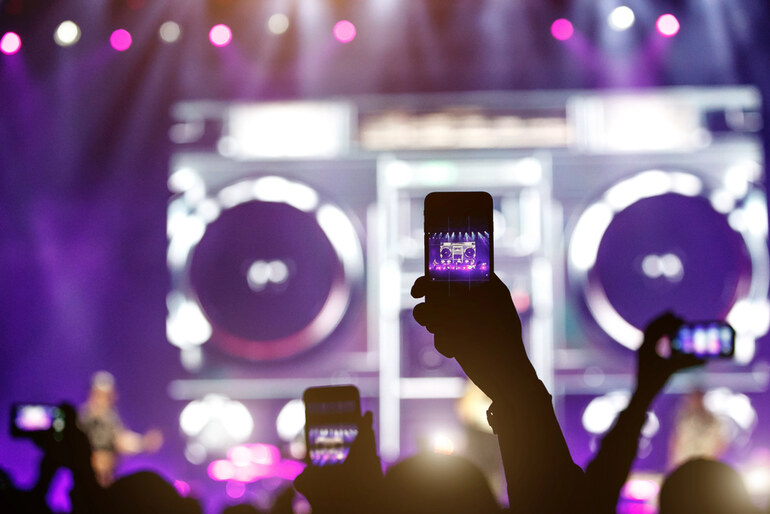 Fans at a live concert holding up smartphones to record the performance