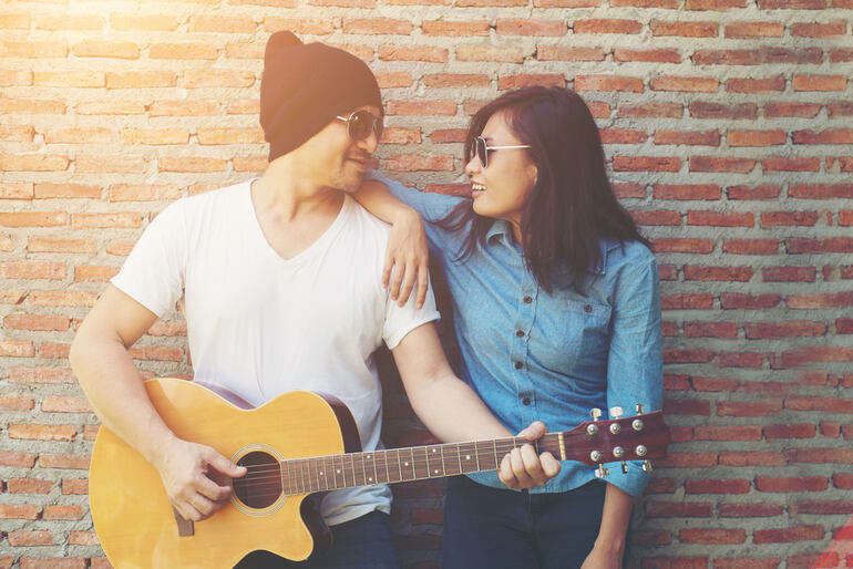 Asian couple bonding over music with an acoustic guitar