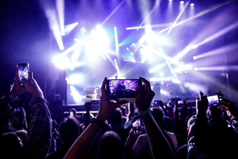 Crowd filming with smartphones at a live music concert with bright stage lights