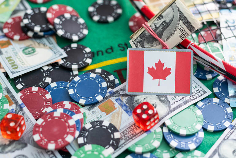 Canadian flag card on a casino table surrounded by poker chips, dice, U.S. dollar bills, and a roll of cash