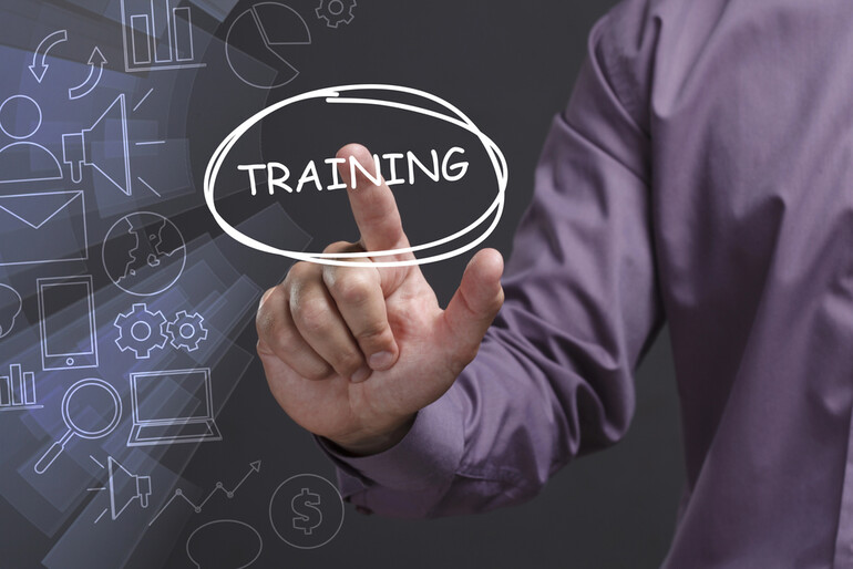 A person in a purple shirt pointing at the word “TRAINING” on a transparent screen interface