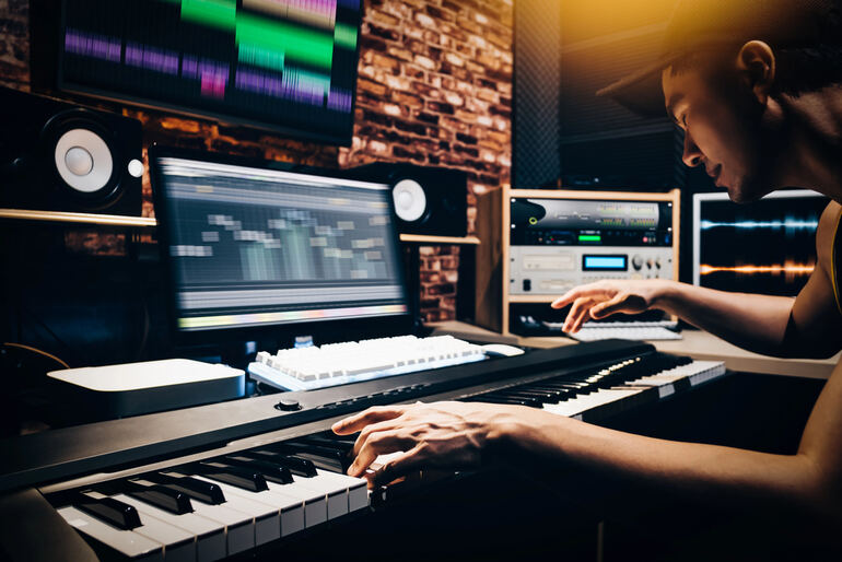 A music producer working on a track in a professional studio setup to get it featured on Beatport