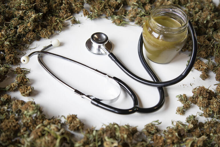 Cannabis buds with a stethoscope and an infused medicine jar representing the link between health, access, and wellness.