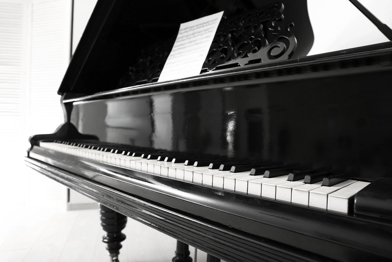 A grand piano with sheet music, representing the study of classical and rock piano styles