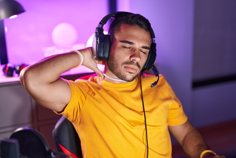 A musician in a headset, stretching his neck while playing a game.