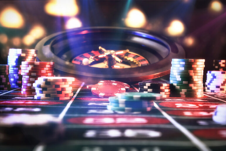 Roulette table with colorful casino chips and spinning wheel under dramatic lights, illustrating the immersive atmosphere enhanced by music-themed slot soundtracks.