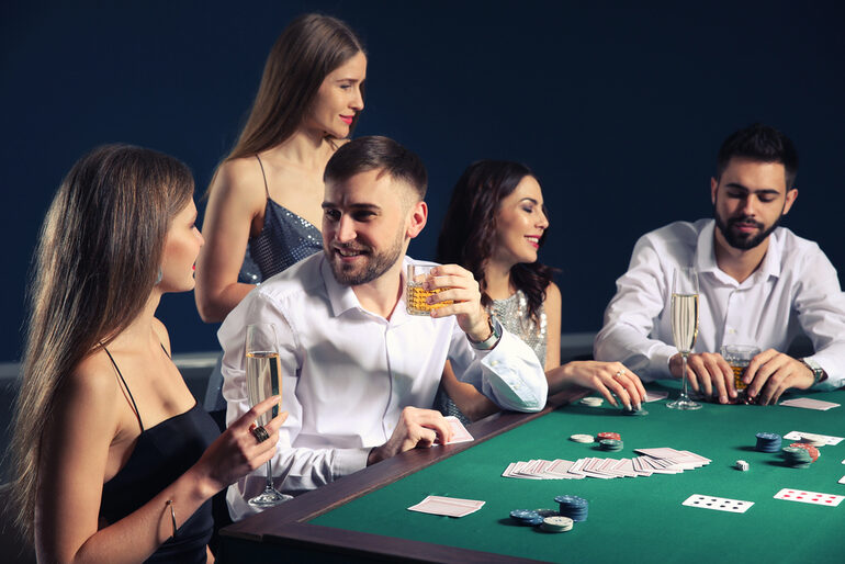 Stylish group of people enjoying drinks and playing poker at a casino table