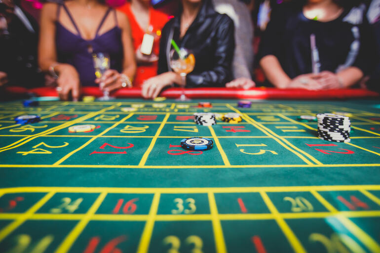 People enjoying a quick game of roulette at a casino table with drinks during a festival break.