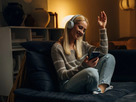 Smiling woman listening to music with headphones while going through a dating app