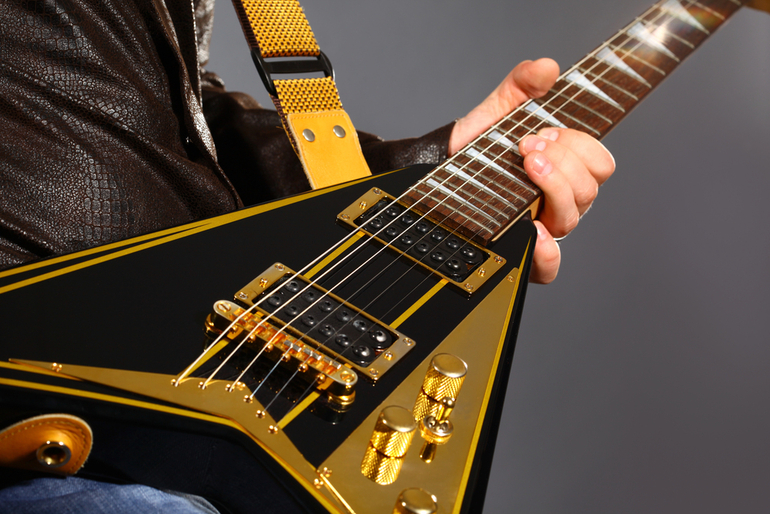 A musician playing a black and gold electric guitar