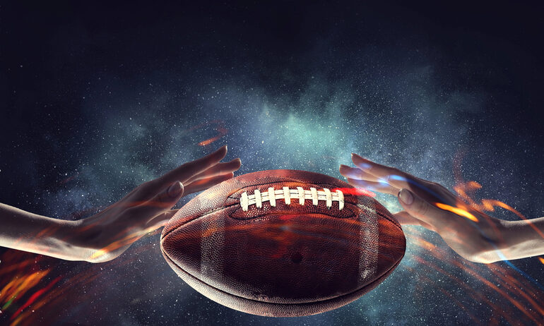 Hands reaching toward an American football against a dramatic cosmic background.