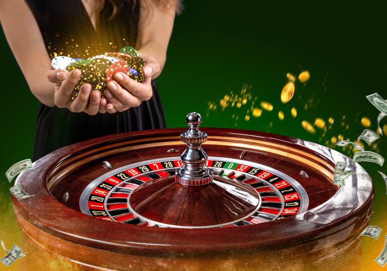 A roulette wheel spinning on a casino table while a woman holds colorful poker chips in her hands, with money and gold coins flying in the background.