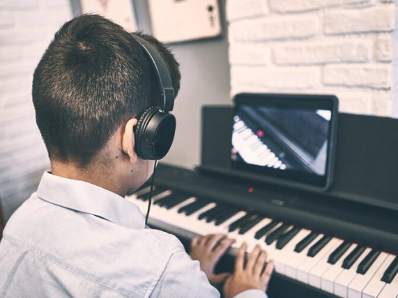 A student learning piano through a digital lesson on a tablet, showing how technology enhances music education.
