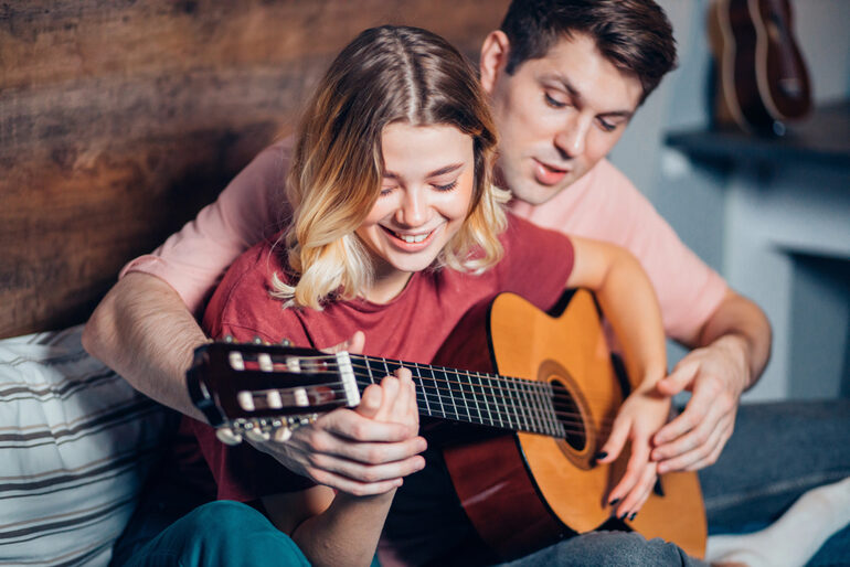 A couple bonding over a guitar lesson, showing how music plays an important part in their dating life.