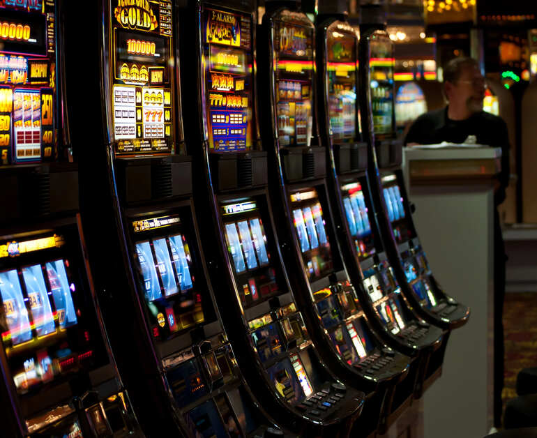 Row of illuminated casino slot machines in a gaming hall, reflecting music-themed casino entertainment.