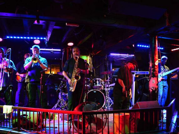 Local band performing live on a small stage under colourful lights, creating a lively community atmosphere.
