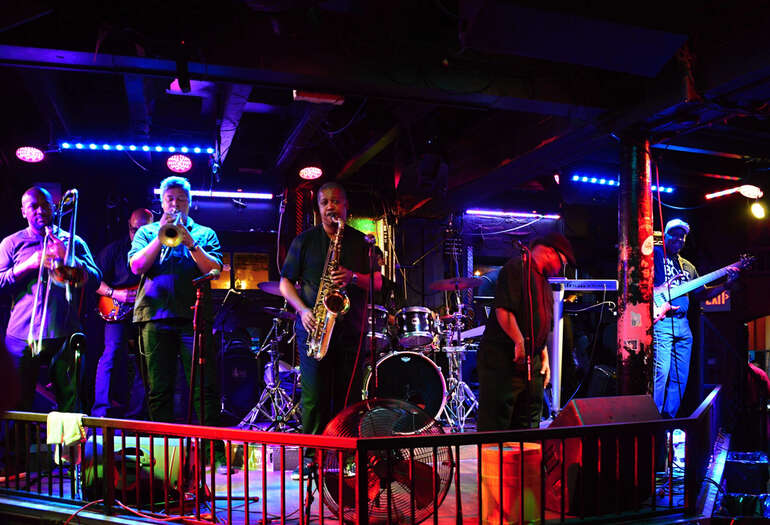 Local band performing live on a small stage under colourful lights, creating a lively community atmosphere.