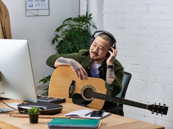 A man is listening to digital music while holding a guitar.
