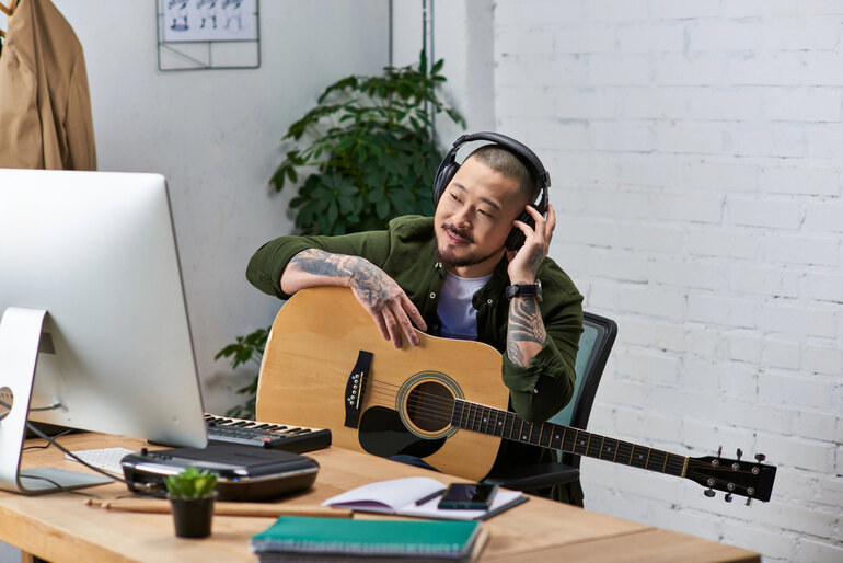 A man is listening to digital music while holding a guitar.