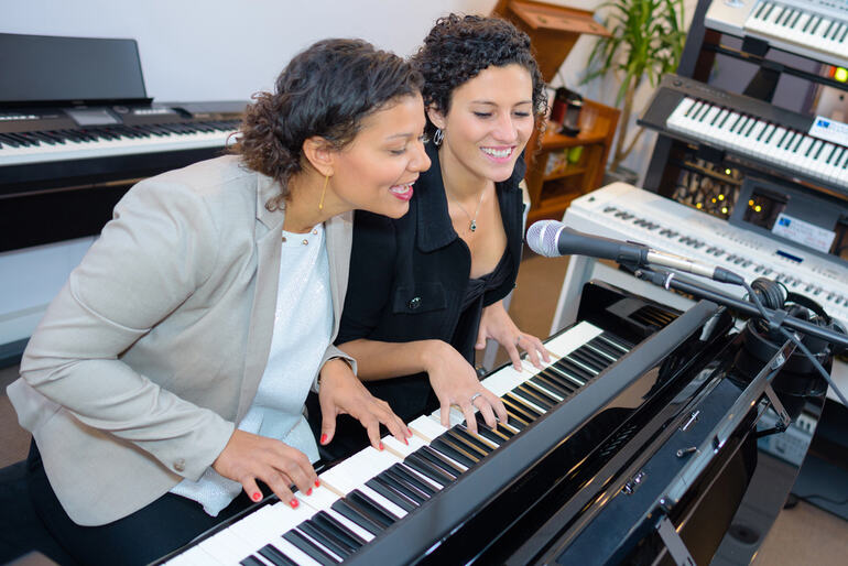 Two piano students of different generations play together and sing into a microphone during a winter recital at a music studio