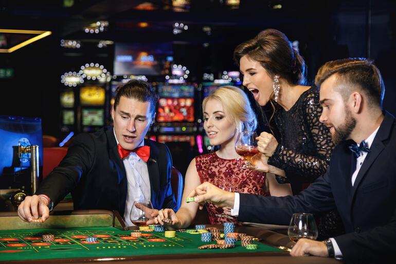 Players at a live casino table closely tracking bets and chip results during a roulette game.