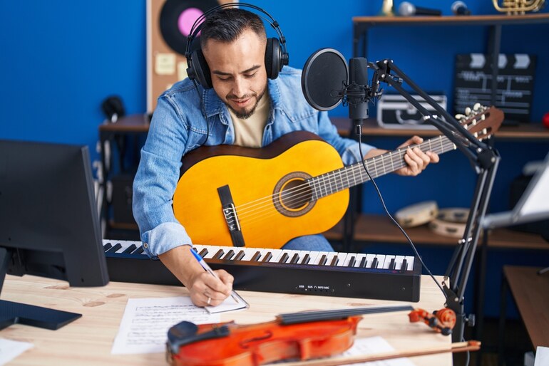 Musician writing song lyrics in a recording studio while playing guitar