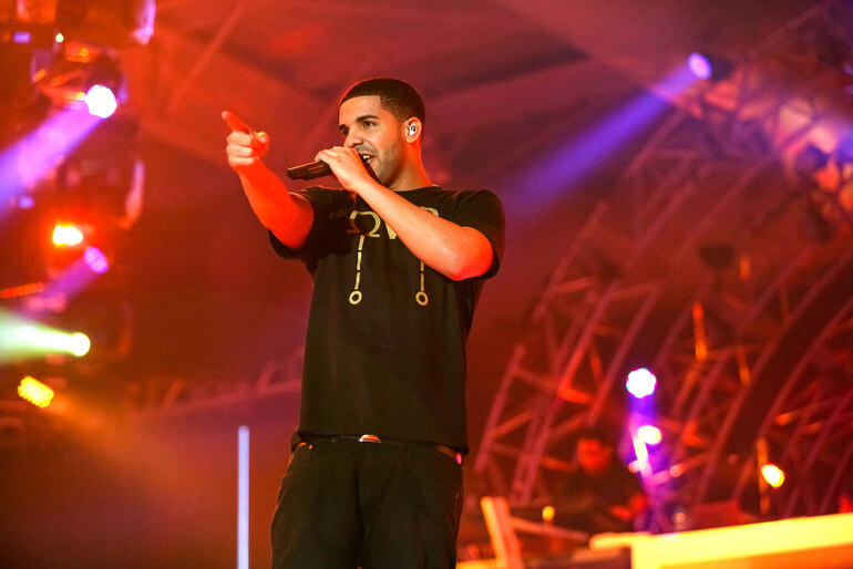 Rapper Drake performing on stage under red and purple concert lights