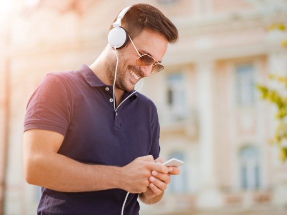 Man listening to music on a smartphone with headphones, enjoying a seamless mobile music experience.