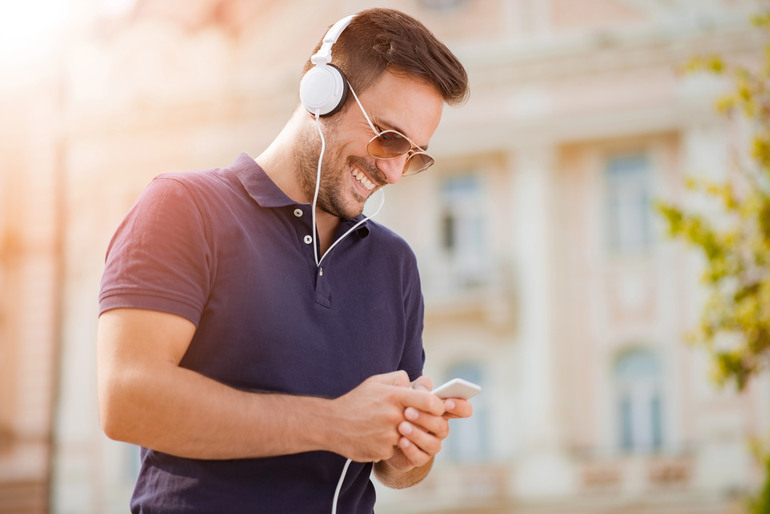 Man listening to music on a smartphone with headphones, enjoying a seamless mobile music experience.