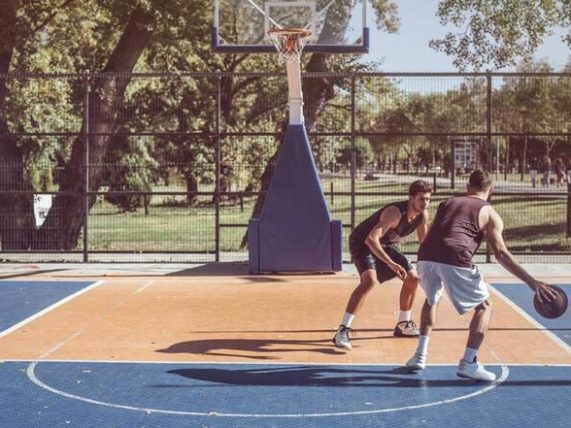 Two men playing outdoor basketball, representing the rise of Bitcoin betting in music culture.