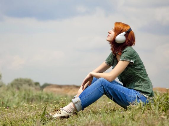 Person relaxing outdoors with headphones, reflecting on music’s impact on self-awareness and mental well-being.