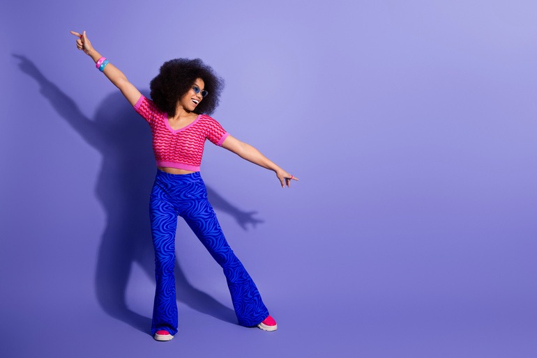 Excited young woman dancing with a joyful expression, reflecting the vibrant energy of the disco-funk and synth-pop revival.