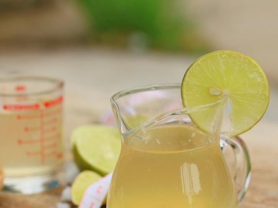 Fresh sugarcane juice in a glass pitcher with lime. 