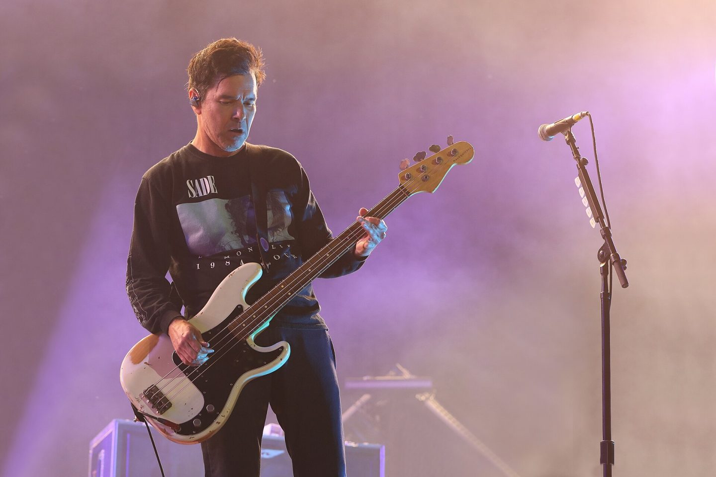 Deftones member playing bass on stage before pink background