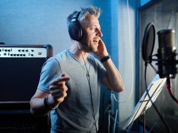 Singer recording in a professional studio, illustrating the journey from bathroom singer to confident stage performer through vocal coaching.