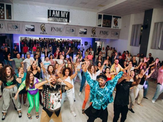 Crowd of dancers with hands raised on a packed dance floor, capturing the energy, excitement, and psychological impact of great music selection that keeps people dancing. 