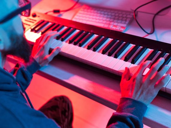 Man composing music on a piano while exploring the relationship between AI tools and human creativity.