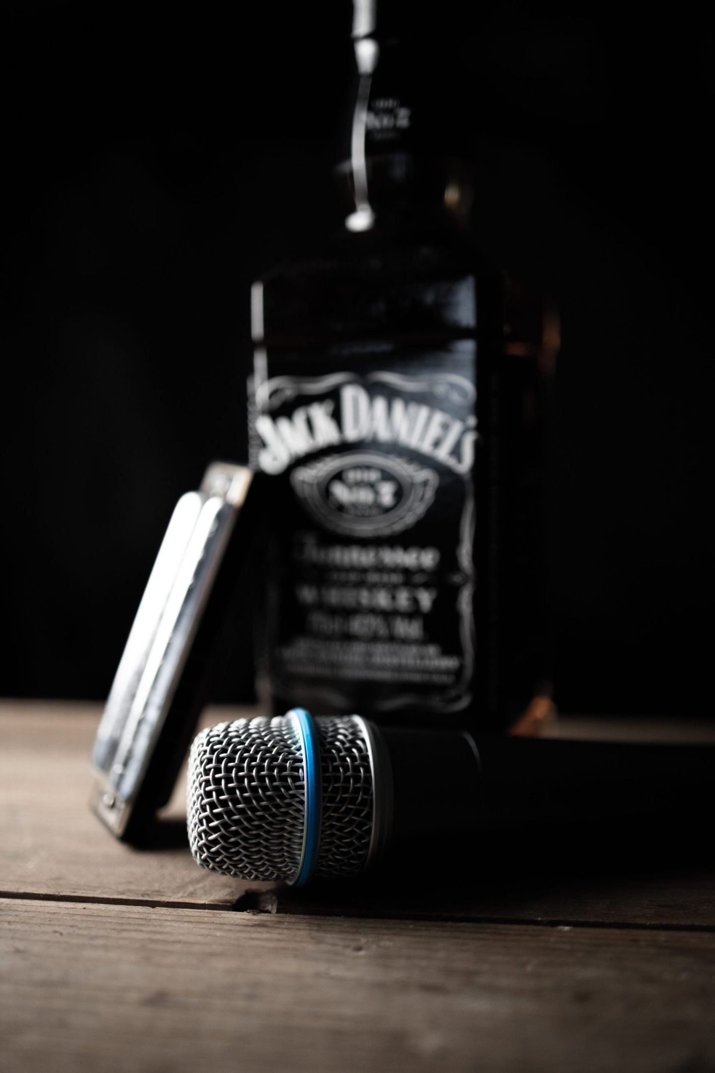 a bottle of whiskey next to a microphone and a harmonica