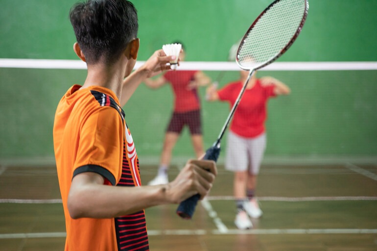 Man playing badminton on an indoor badminton court in Malaysia.