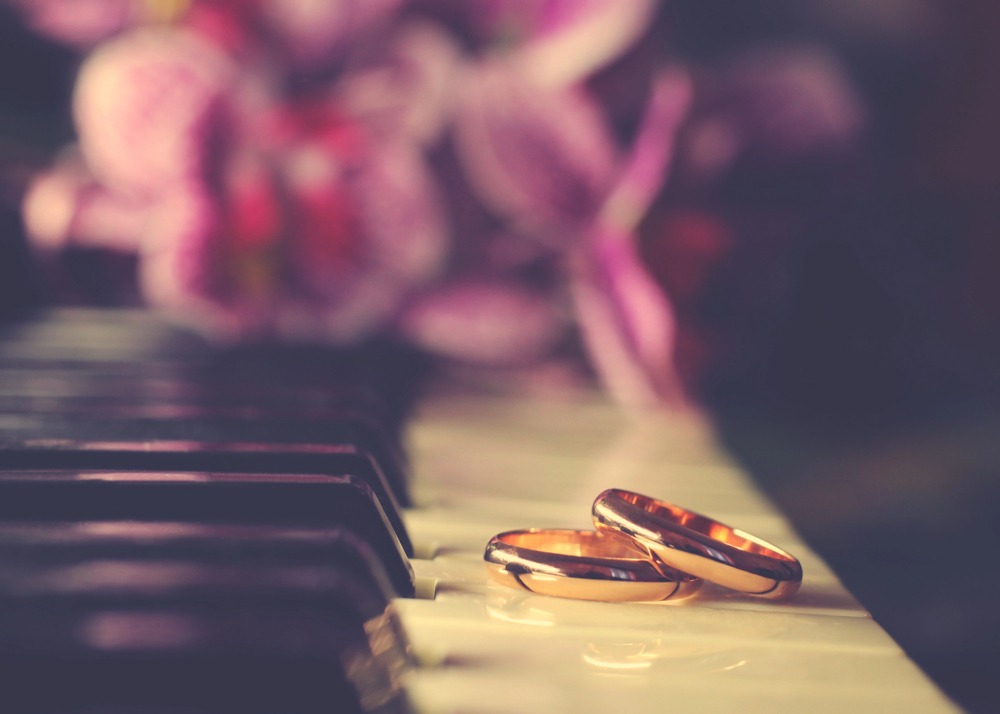 Two sleek gold wedding rings with the piano keys in a concert piano.